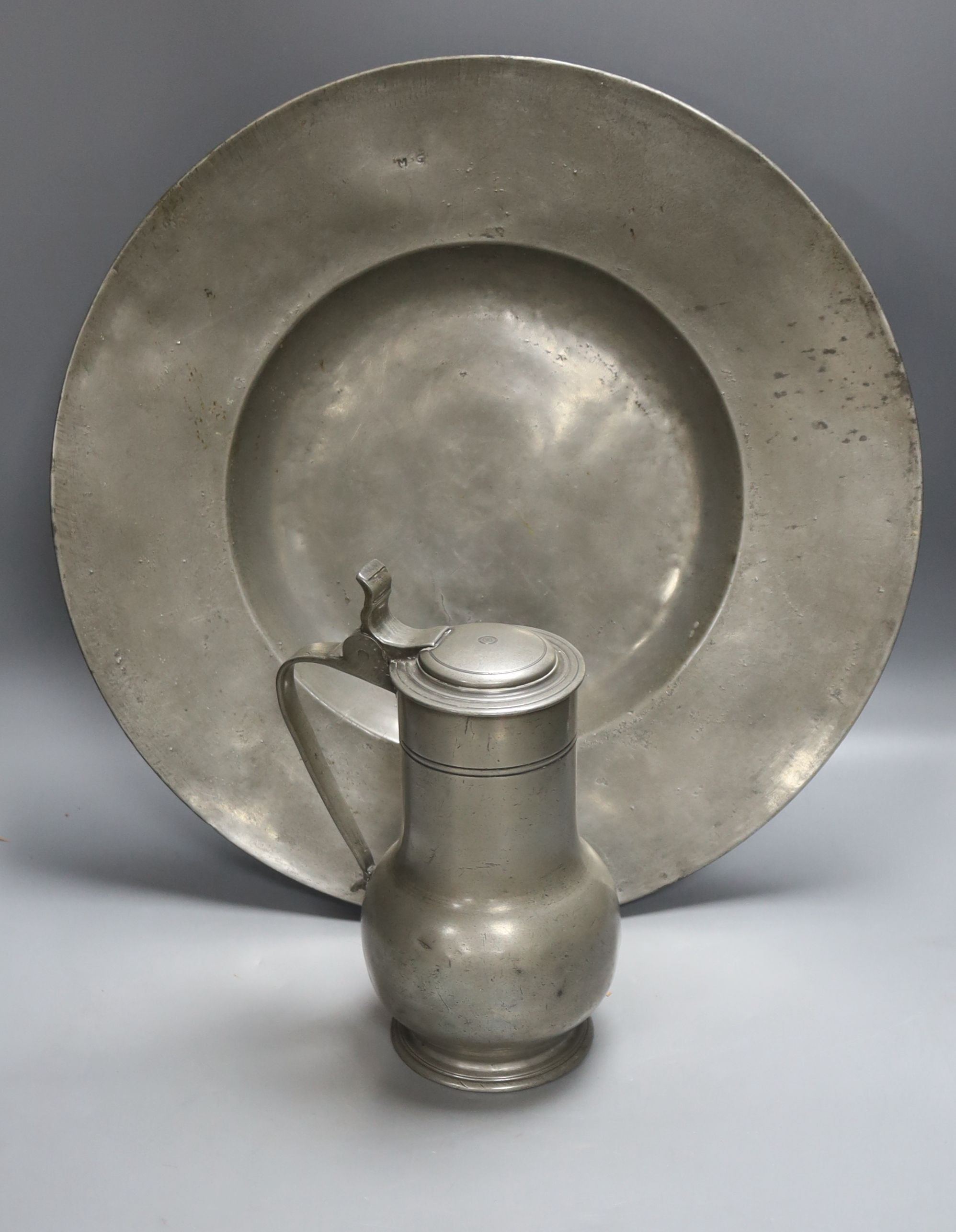 A 17th century pewter charger (possibly Nicholas Kelk) 47cm and a late 17th century pewter flagon, 25.5cm